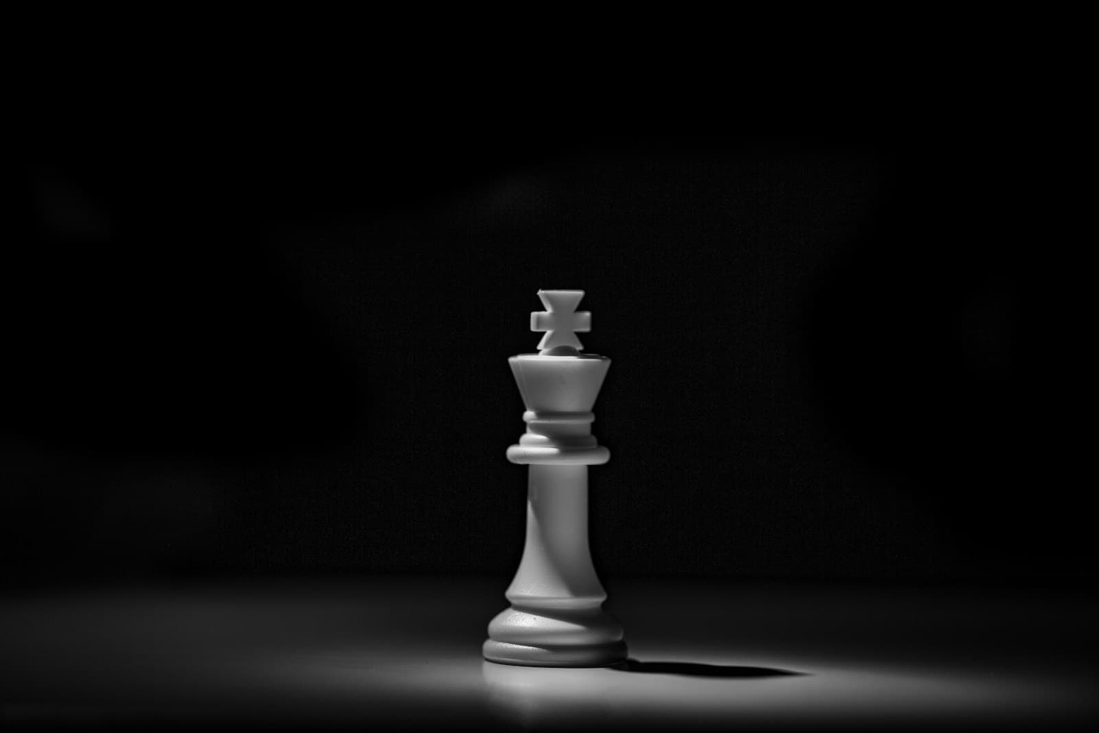 A white chess king under a single spotlight